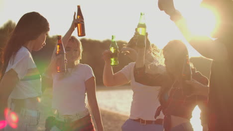 Los-Estudiantes-Disfrutan-De-Una-Fiesta-De-Verano-Al-Aire-Libre-En-La-Playa-Con-Cerveza.-Están-Bailando-En-La-Costa-Del-Río-Y-Divirtiéndose-En-La-Naturaleza.
